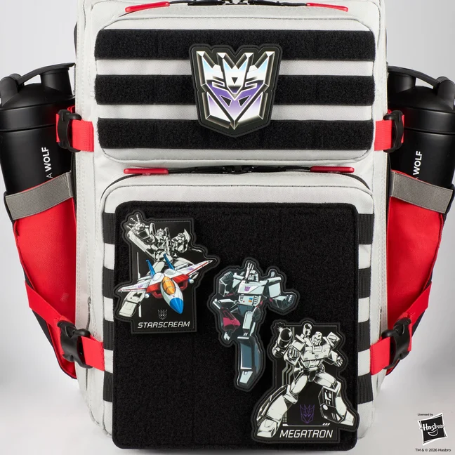 A grey and black tactical backpack with four Decepticon patches attached. A purple and silver Decepticon crest sits on the upper hook and loop strip. On the black panel below it, a patch of Starscream in jet mode labelled STARSCREAM, an unlabelled patch of Megatron in robot mode, and a patch of Megatron holding a weapon labelled MEGATRON.