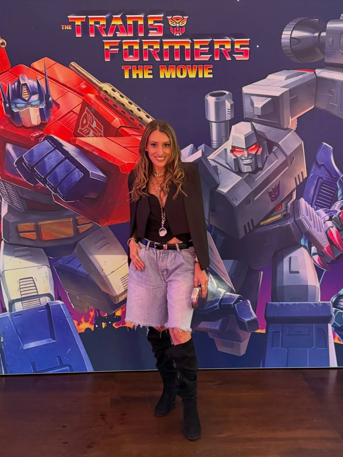 A guest standing in front of the large Optimus Prime and Megatron artwork standee for The Transformers The Movie